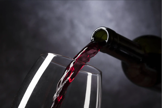 Red wine being poured from a bottle into a clear wine glass