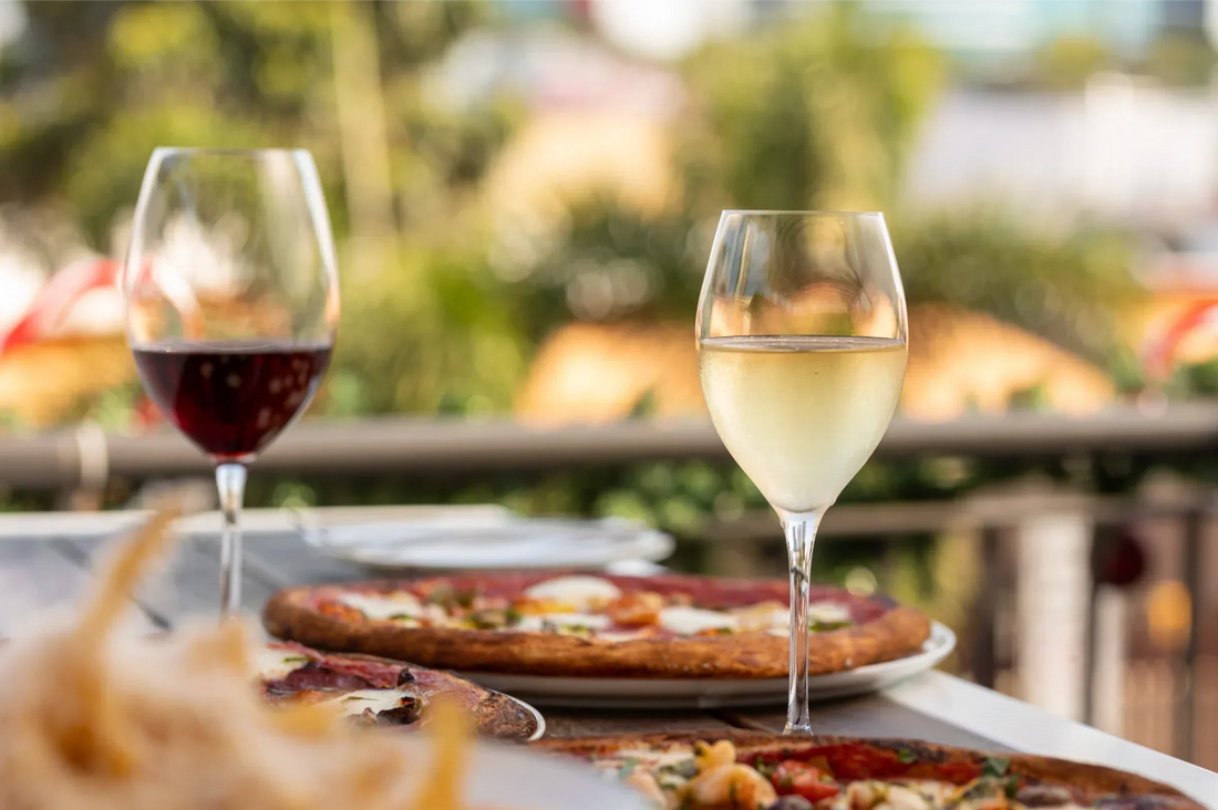 Pizza slices with glasses of red and white wine, showing the best wine pairings for pizza night