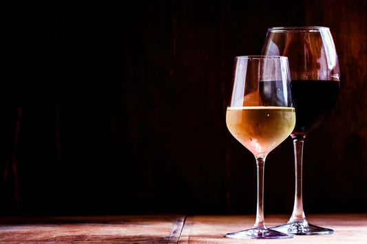 Glass of dry white wine and glass of dry red wine on a rustic wooden table with dark background