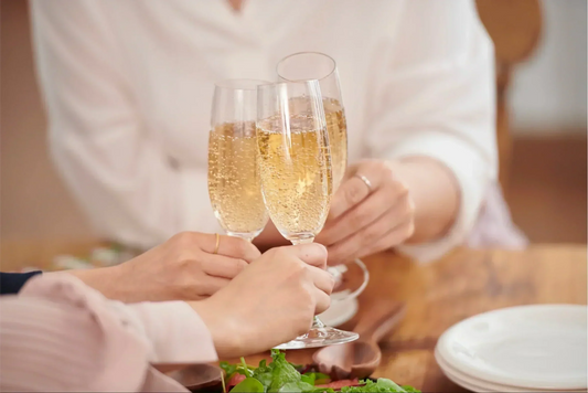 Friends toasting with glasses of canned sparkling wine at a table, showcasing top canned sparkling wines to try in 2025