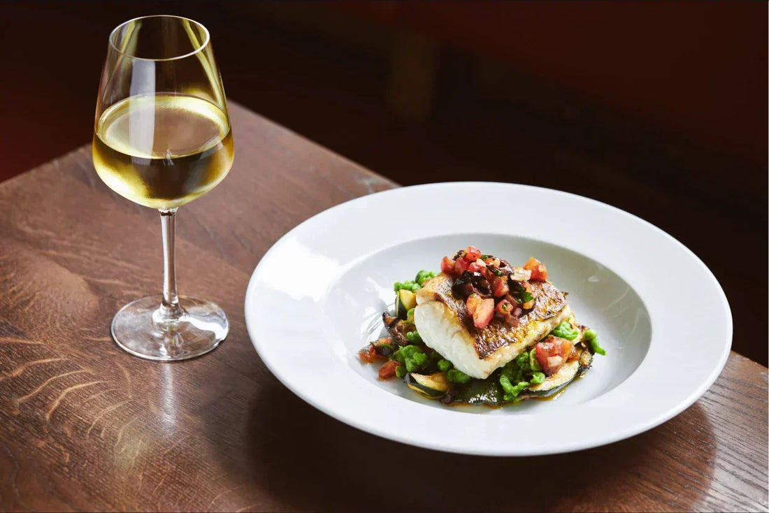 Glass of white wine served with pan-fried fish and vegetables, perfect wine and fish pairing