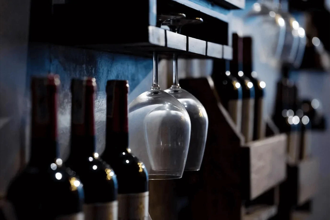 Home wine storage setup with bottles on racks and hanging glasses in a dark, cool space.