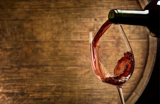 Red wine being poured into a glass in front of a wooden barrel, highlighting wine tannins