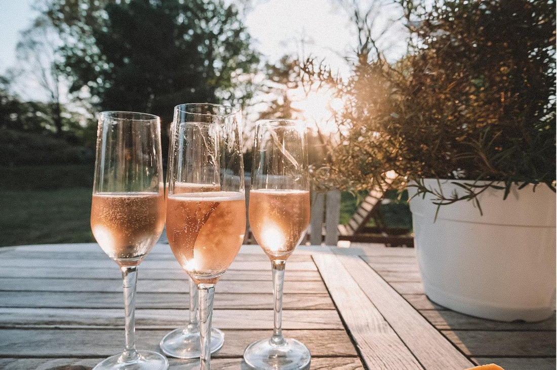 Glasses of chilled sparkling rosé wine served outdoors on a summer evening table, perfect for celebrations and alfresco dining.